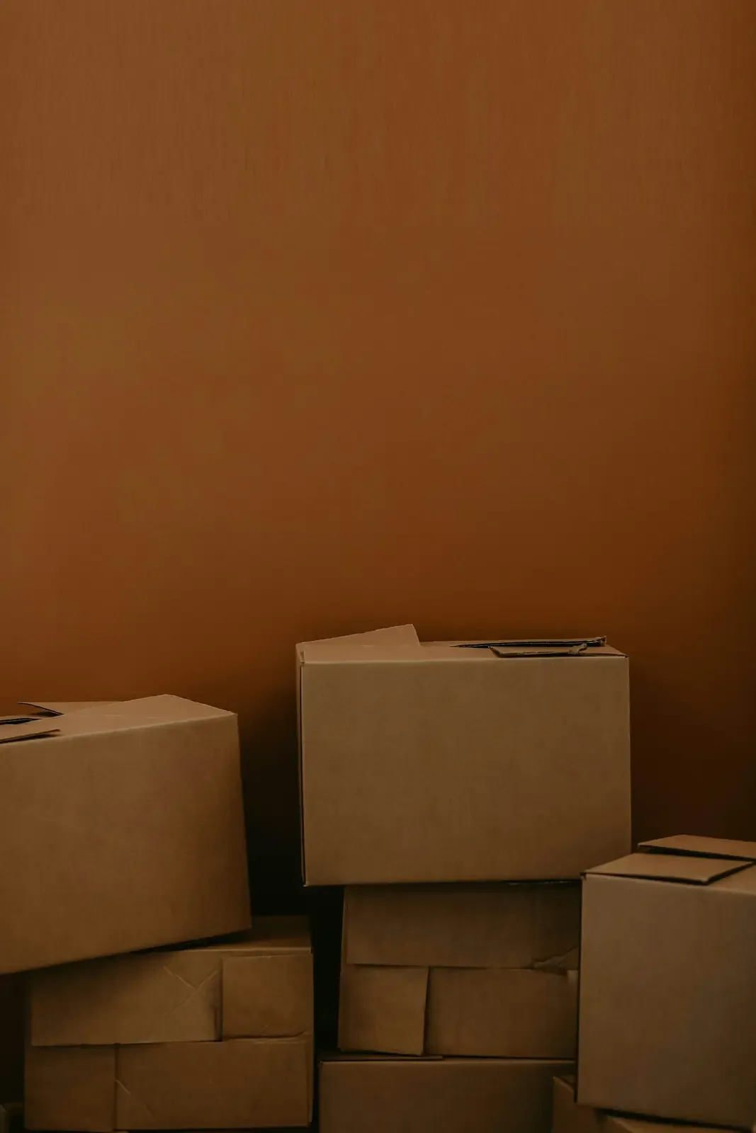 Moving boxes stacked against a warm brown wall