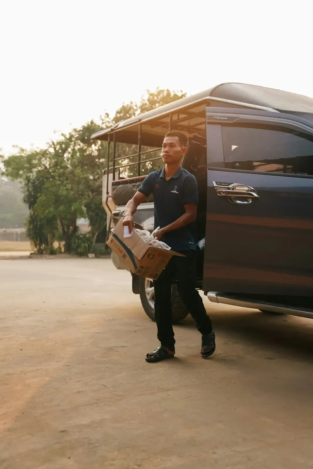 A mover carrying a box to a van at golden hour